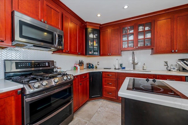 137 Jefferson St, Inwood, NY 11096 - kitchen featuring stainless steel appliances, backsplash, light countertops, reddish brown cabinets, and recessed lighting