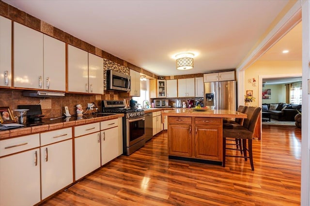 137 Jefferson St, Inwood, NY 11096 - kitchen with stainless steel appliances, dark wood-type flooring, a breakfast bar, and backsplash