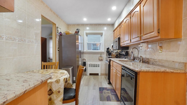 2334 Belmont Ave, Elmont, NY 11003 - kitchen with tile walls, appliances with stainless steel finishes, radiator, light stone countertops, and light wood-style floors