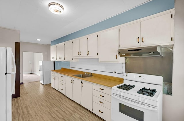 29 William St, Ossining, NY 10562 - kitchen with white appliances, under cabinet range hood, white cabinets, light countertops, and light wood-style floors