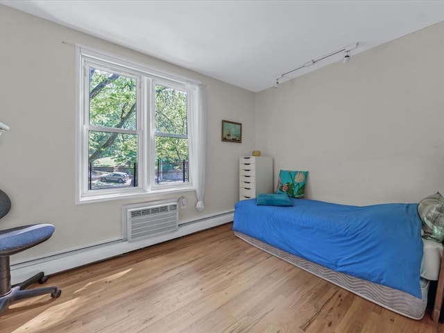 42-30 Douglaston Pkwy Unit 3L, Douglaston, NY 11363 - bedroom featuring a wall mounted AC, wood finished floors, rail lighting, and a baseboard radiator
