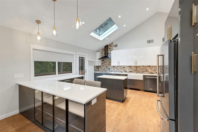 182 Arbor Crst, Somers, NY 10589 - kitchen with a skylight, stainless steel appliances, wall chimney range hood, light wood-style floors, and white cabinets