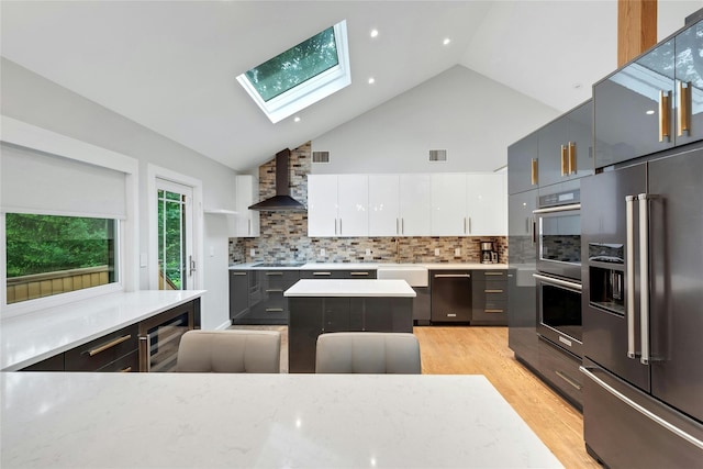 182 Arbor Crst, Somers, NY 10589 - kitchen with wall chimney exhaust hood, appliances with stainless steel finishes, a skylight, light wood-type flooring, and white cabinets
