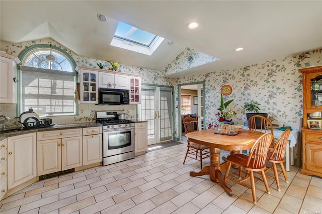121 6th St, Hicksville, NY 11801 - kitchen featuring stainless steel gas range, vaulted ceiling, black microwave, a skylight, and wallpapered walls