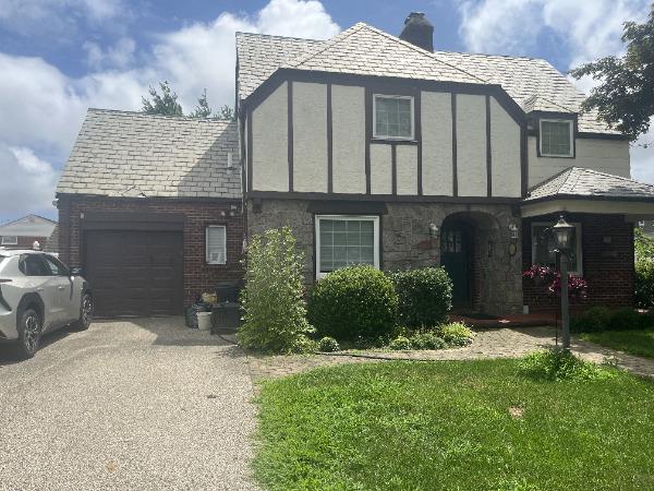 121 6th St, Hicksville, NY 11801 - tudor house with a garage, driveway, a chimney, and stone siding