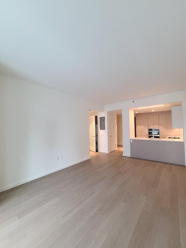 133-27 39th Ave, Flushing, NY 11354 - unfurnished living room featuring light wood-style floors and baseboards