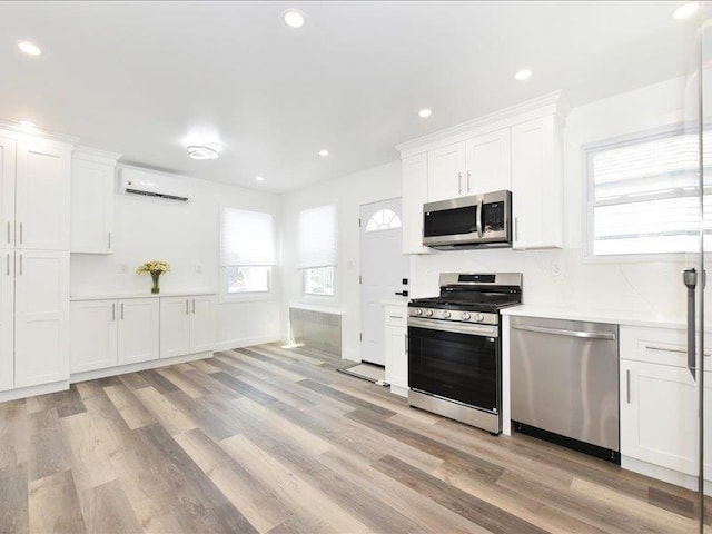 180 Evelyn Rd, Mineola, NY 11501 - kitchen featuring stainless steel appliances, an AC wall unit, light wood-style floors, plenty of natural light, and recessed lighting