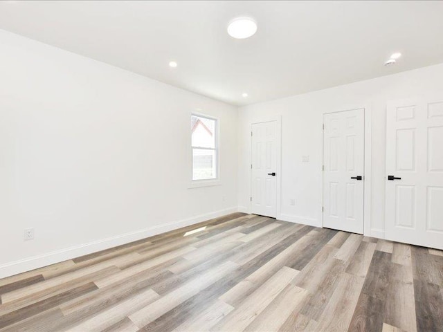 180 Evelyn Rd, Mineola, NY 11501 - unfurnished bedroom with light wood-type flooring, multiple closets, and recessed lighting
