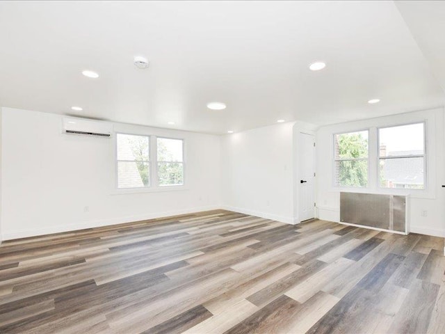 180 Evelyn Rd, Mineola, NY 11501 - empty room featuring an AC wall unit, healthy amount of natural light, wood finished floors, and recessed lighting