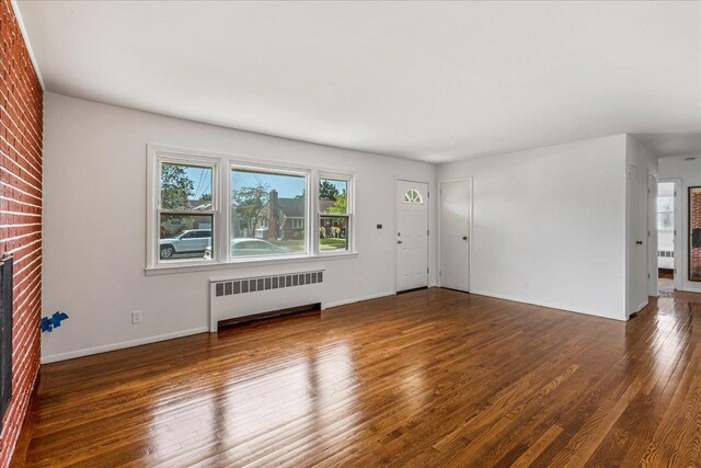19 Dakota St, Hicksville, NY 11801 - unfurnished living room featuring radiator, wood finished floors, and a brick fireplace