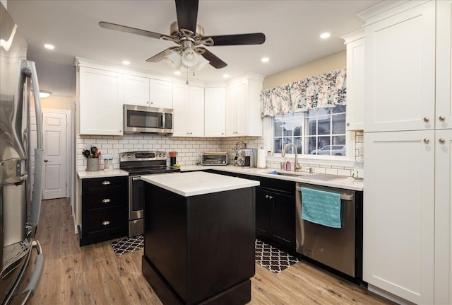 86 Shepherd Ln, Levittown, NY 11756 - kitchen featuring stainless steel appliances, dark cabinetry, light wood finished floors, white cabinets, and recessed lighting
