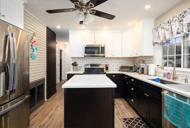 86 Shepherd Ln, Levittown, NY 11756 - kitchen with stainless steel appliances, a kitchen island, white cabinets, dark cabinetry, and tasteful backsplash