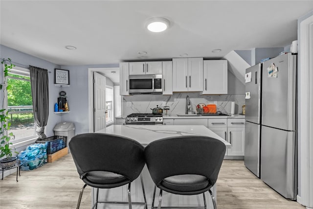 17 Sterling St, Middletown, NY 10940 - kitchen featuring stainless steel appliances, white cabinets, light wood-type flooring, tasteful backsplash, and a kitchen breakfast bar