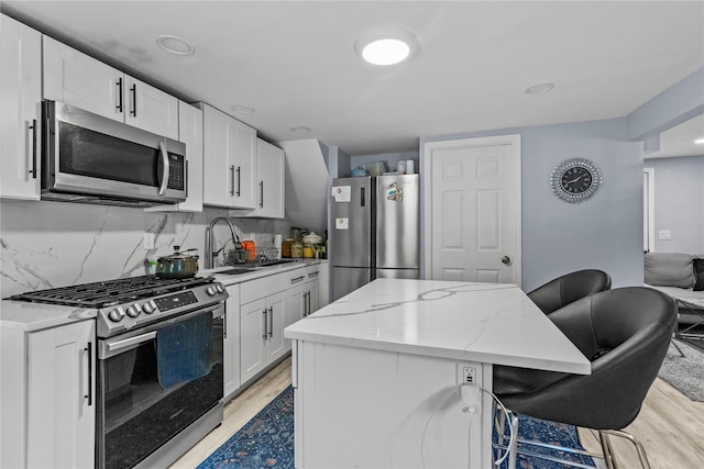 17 Sterling St, Middletown, NY 10940 - kitchen featuring appliances with stainless steel finishes, light wood-type flooring, a breakfast bar area, a center island, and light stone counters