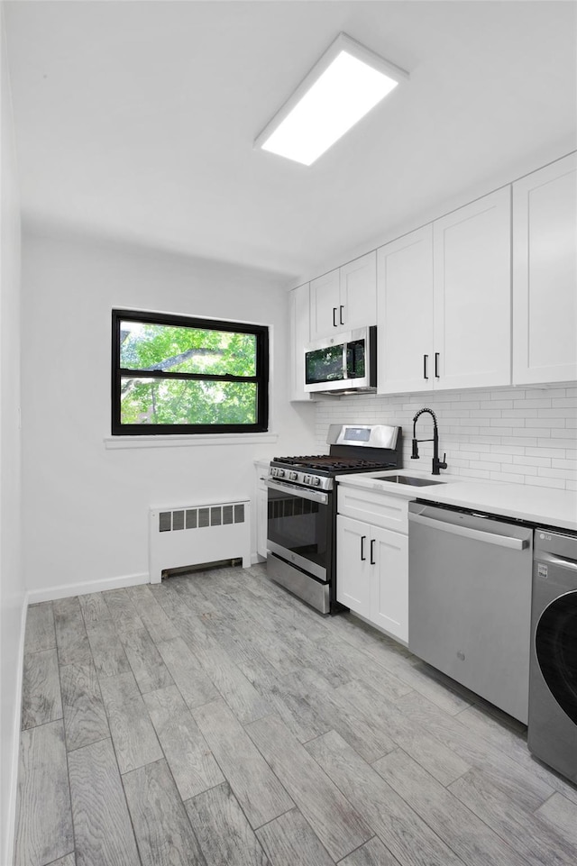 75-02 Springfield Blvd Fl 2Nd, Bayside, NY 11364 - kitchen with stainless steel appliances, radiator heating unit, washer / dryer, decorative backsplash, and white cabinetry