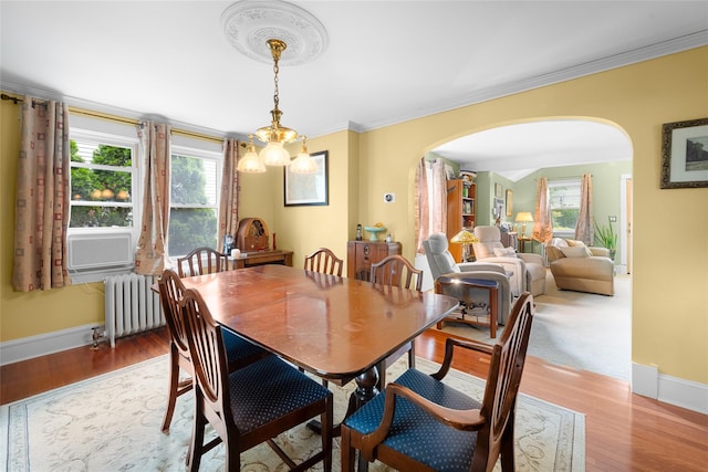 27 Neulist Ave, Port Washington, NY 11050 - dining space featuring arched walkways, radiator, ornamental molding, wood finished floors, and a chandelier