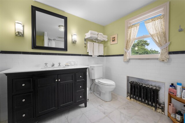 27 Neulist Ave, Port Washington, NY 11050 - bathroom featuring radiator heating unit, tile walls, wainscoting, vanity, and marble finish floors