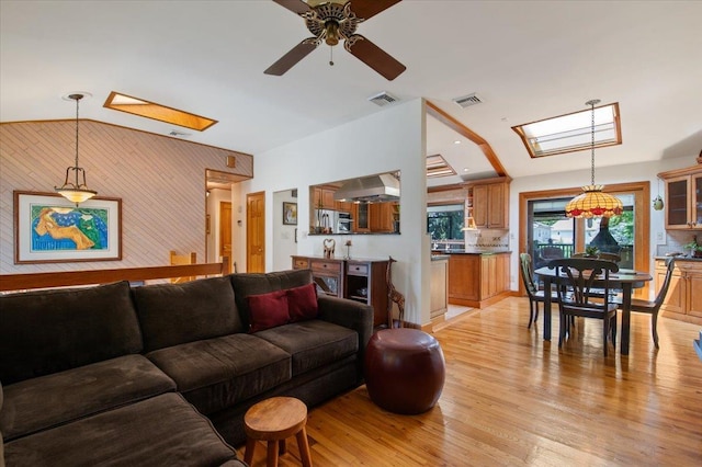 713 Thomas Ave, Baldwin, NY 11510 - living area with a skylight, a ceiling fan, light wood-style floors, lofted ceiling, and wood walls