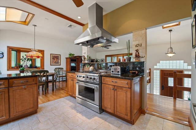 713 Thomas Ave, Baldwin, NY 11510 - kitchen featuring island range hood, stainless steel stove, brown cabinets, backsplash, and a ceiling fan