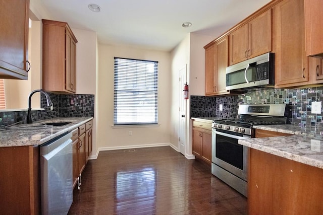 49 Cornwall Ln, Middletown, NY 10940 - kitchen featuring stainless steel appliances, dark wood finished floors, decorative backsplash, brown cabinetry, and light stone counters