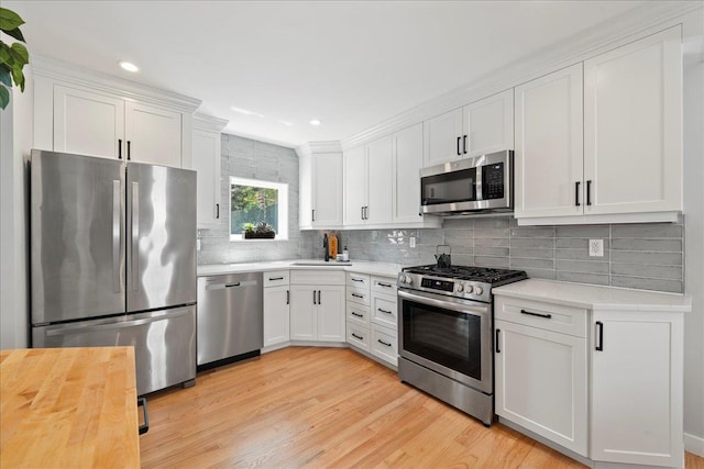 56 Summers St, Oyster Bay, NY 11771 - kitchen with stainless steel appliances, white cabinets, light wood-style floors, backsplash, and recessed lighting