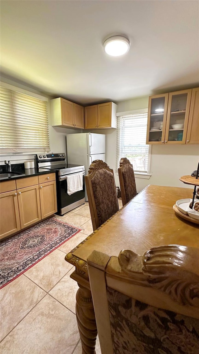14 Upper Ferndale Rd, Liberty, NY 12754 - kitchen with electric range, light tile patterned floors, glass insert cabinets, dark countertops, and freestanding refrigerator