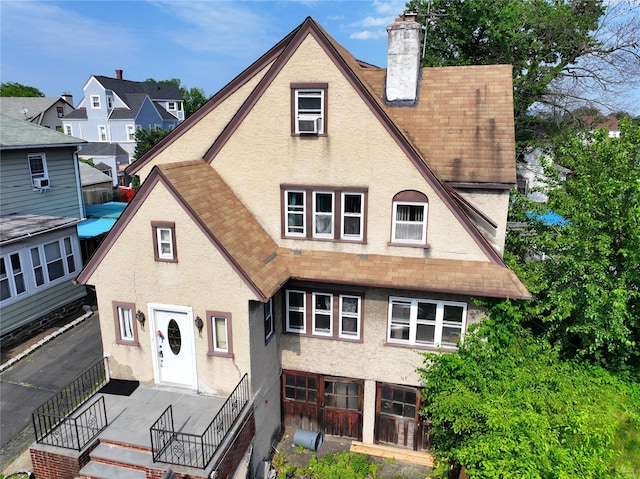 279 Bedford Ave, Mount Vernon, NY 10553 - view of front of property featuring stucco siding, a shingled roof, a chimney, and cooling unit