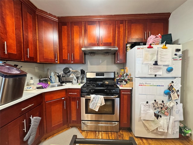 43-53 159th St, Flushing, NY 11358 - kitchen featuring freestanding refrigerator, stainless steel range with gas stovetop, ventilation hood, reddish brown cabinets, and light wood-type flooring