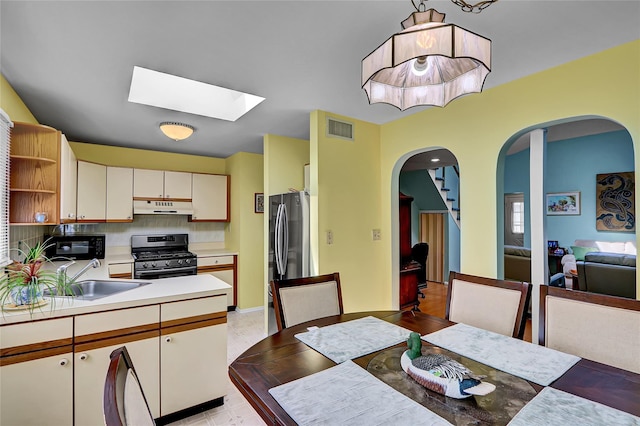 49 Primrose Ln, North Babylon, NY 11703 - kitchen with appliances with stainless steel finishes, under cabinet range hood, open shelves, arched walkways, and light countertops