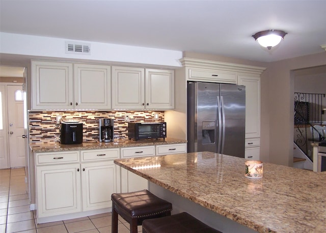13 Lark Dr, Centereach, NY 11720 - kitchen with stainless steel fridge, light tile patterned floors, decorative backsplash, a kitchen bar, and light stone counters