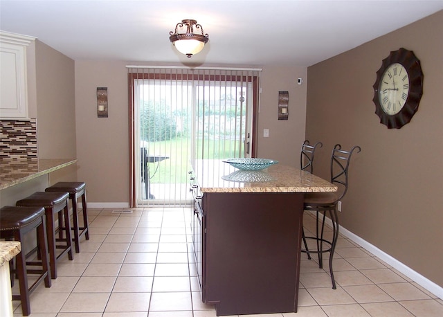 13 Lark Dr, Centereach, NY 11720 - kitchen featuring a kitchen bar, light tile patterned flooring, backsplash, white cabinetry, and a kitchen island