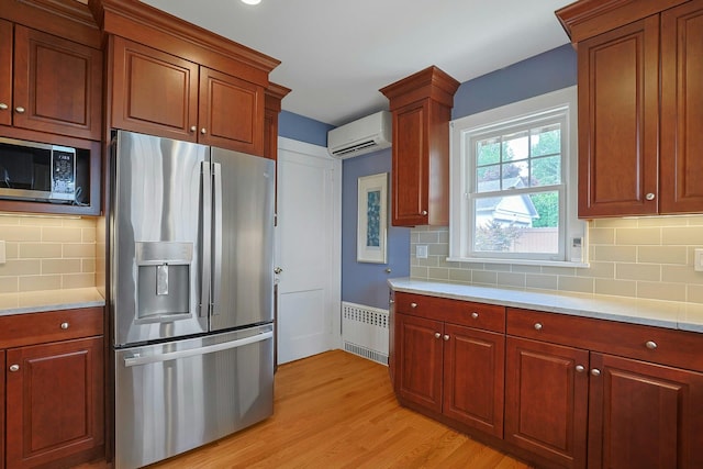 48 Faneuil Pl, New Rochelle, NY 10801 - kitchen with appliances with stainless steel finishes, a wall mounted air conditioner, radiator, light countertops, and light wood-type flooring