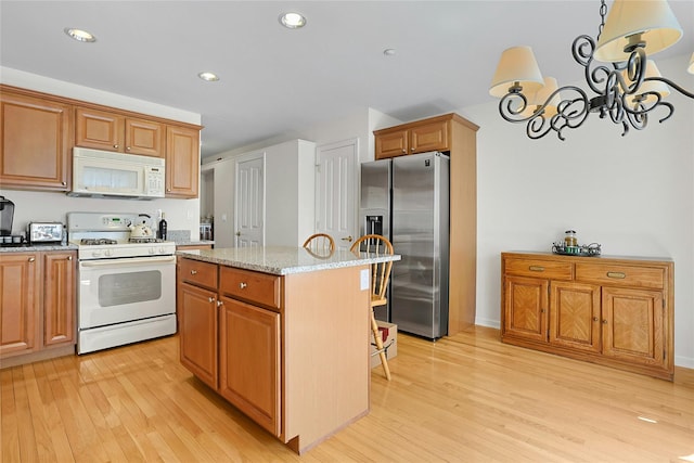 23 Bridge Ln Unit 23, Haverstraw, NY 10927 - kitchen with white appliances, light wood-style flooring, a chandelier, a center island, and light stone countertops