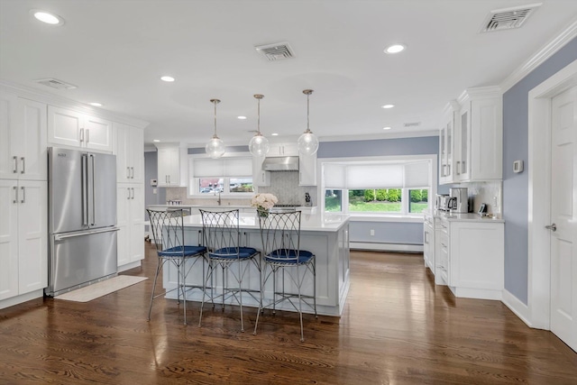 14 Ridge Dr E, Roslyn, NY 11576 - kitchen featuring high end refrigerator, baseboard heating, under cabinet range hood, white cabinets, and light countertops