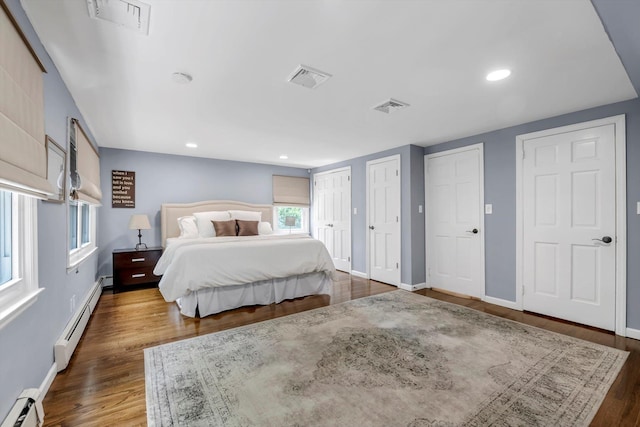 14 Ridge Dr E, Roslyn, NY 11576 - bedroom with baseboard heating, two closets, wood finished floors, and recessed lighting