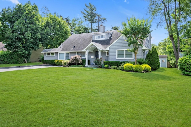 14 Ridge Dr E, Roslyn, NY 11576 - view of front facade featuring a front yard, a chimney, and a storage unit