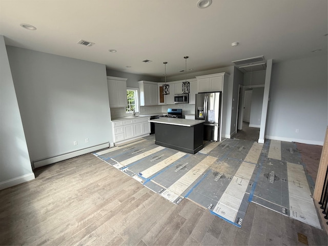 47 Sheridan Ave, Congers, NY 10920 - kitchen featuring baseboard heating, stainless steel appliances, a kitchen island, white cabinets, and light countertops