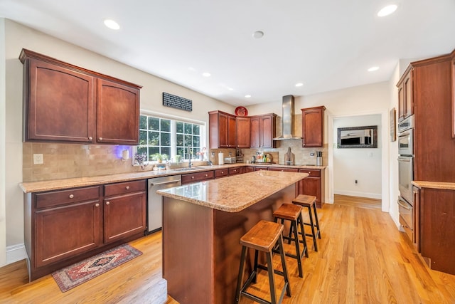 212A Lower Sheep Pasture Rd, East Setauket, NY 11733 - kitchen featuring stainless steel appliances, wall chimney exhaust hood, light wood-style floors, a breakfast bar area, and a kitchen island