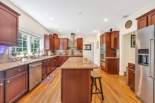 212A Lower Sheep Pasture Rd, East Setauket, NY 11733 - kitchen featuring stainless steel appliances, wall chimney exhaust hood, a warming drawer, light wood-style floors, and a center island