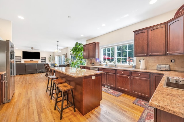 212A Lower Sheep Pasture Rd, East Setauket, NY 11733 - kitchen with open floor plan, light wood-style floors, tasteful backsplash, a breakfast bar area, and a center island