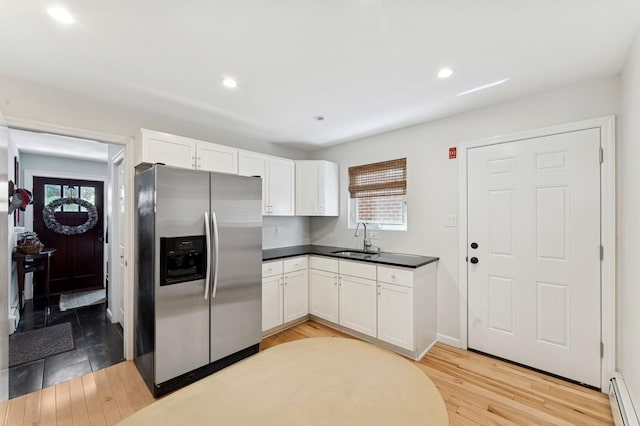 101 Connecticut Ave, Long Beach, NY 11561 - kitchen featuring stainless steel fridge with ice dispenser, a baseboard radiator, white cabinetry, dark countertops, and light wood-style flooring