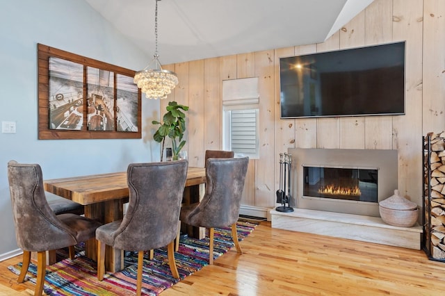 101 Connecticut Ave, Long Beach, NY 11561 - dining area with lofted ceiling, wood finished floors, a chandelier, wooden walls, and a glass covered fireplace