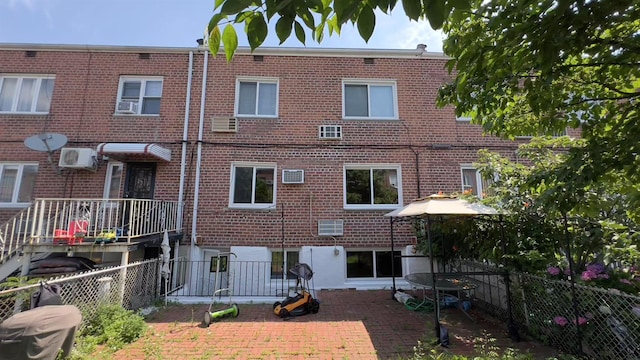 61-56 70th St, Middle Village, NY 11379 - back of property with a patio area, brick siding, and a wall mounted AC