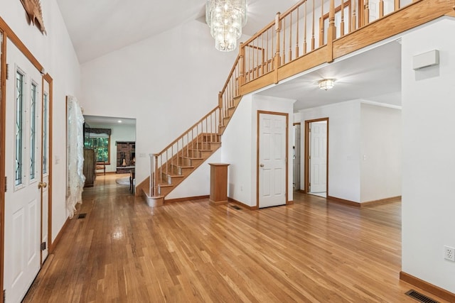 4 Springview Ct, East Patchogue, NY 11772 - foyer with wood finished floors, stairs, a high ceiling, a fireplace, and a chandelier