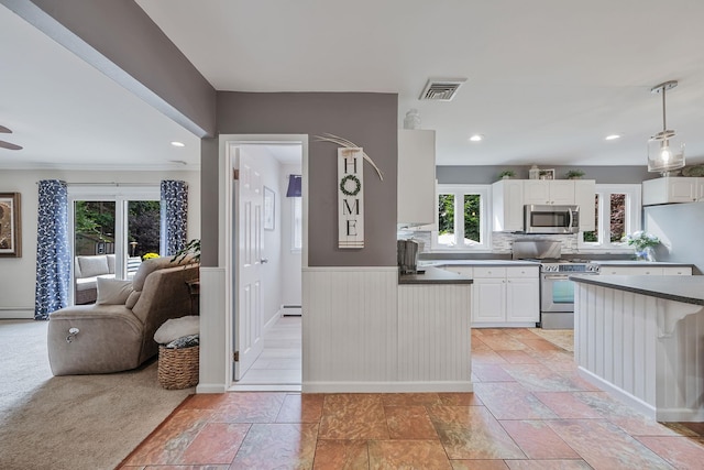 7 Simon Ct, East Northport, NY 11731 - kitchen featuring stainless steel appliances, dark countertops, healthy amount of natural light, white cabinets, and a wainscoted wall