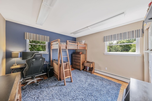 7 Simon Ct, East Northport, NY 11731 - bedroom with a baseboard heating unit, multiple windows, wood finished floors, and an office area