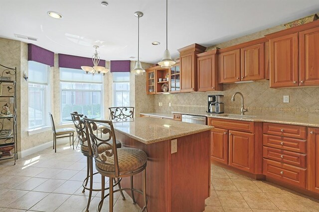 27 Bridge Ln, Haverstraw, NY 10927 - kitchen with light tile patterned floors, a kitchen island, light stone counters, decorative backsplash, and brown cabinetry