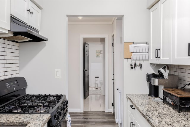 95 Pointe Cir S Unit 95, Coram, NY 11727 - kitchen with black gas range oven, under cabinet range hood, white cabinets, tasteful backsplash, and light stone countertops