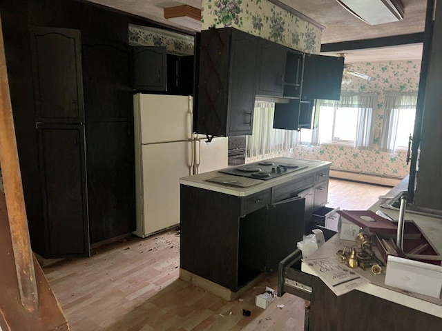 16 Bethlehem Pl, Poughkeepsie, NY 12603 - kitchen with wallpapered walls, light wood-type flooring, freestanding refrigerator, black electric stovetop, and dark cabinetry