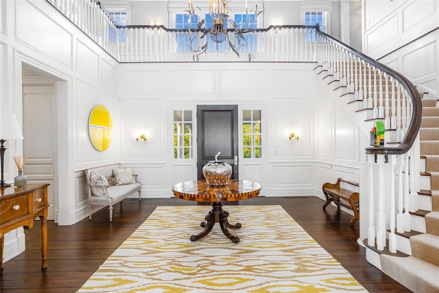 59 Shore Rd, Westhampton, NY 11977 - entrance foyer with a decorative wall, a chandelier, dark wood-type flooring, stairs, and a towering ceiling